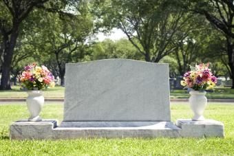 Lápide em branco no cemitério com flores