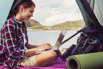 Donna cù laptop in tenda in muntagna