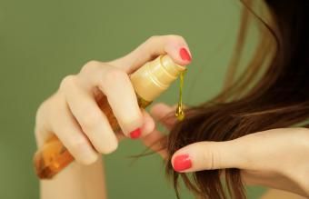 Жена, прилагаща масло върху краищата на косата