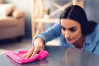 Kobieta używa ścierki do kurzu podczas sprzątania mebli w domu
