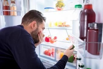 Homem percebendo cheiro vindo de comida suja na geladeira