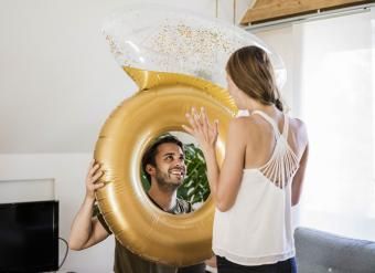 Homem sorridente olhando para a namorada através de um grande anel inflável