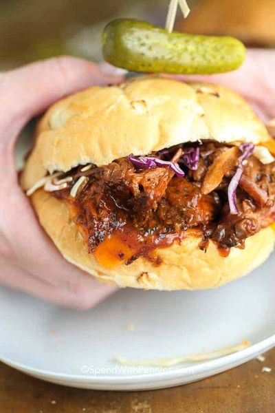 Slow Cooker BBQ Pulled Beef Sandwich di tangan seseorang