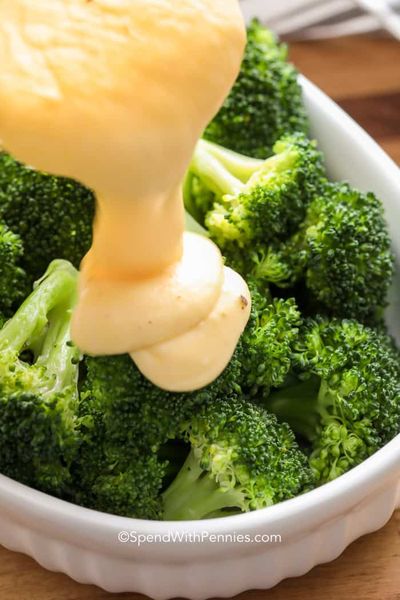 Derramando o molho de queijo sobre brócolis